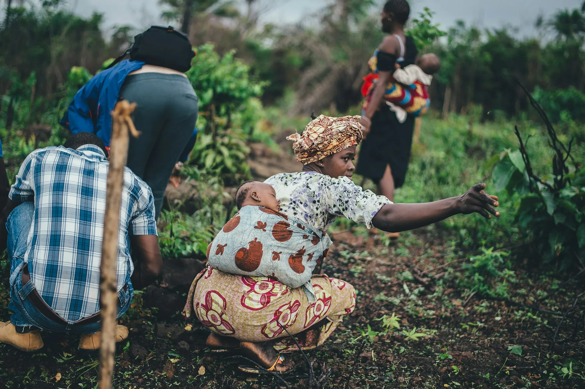 A woman working in agriculture with a young child nearby.
